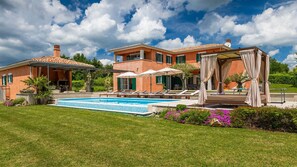 A two-story house with a swimming pool, outdoor seating, and a pergola with curtains. - Villa Village by Villas Guide (Tinjan)