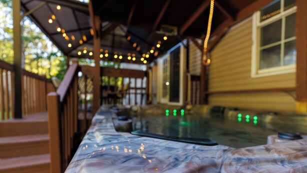 Un área de hidromasaje con terraza de madera y luces colgantes.