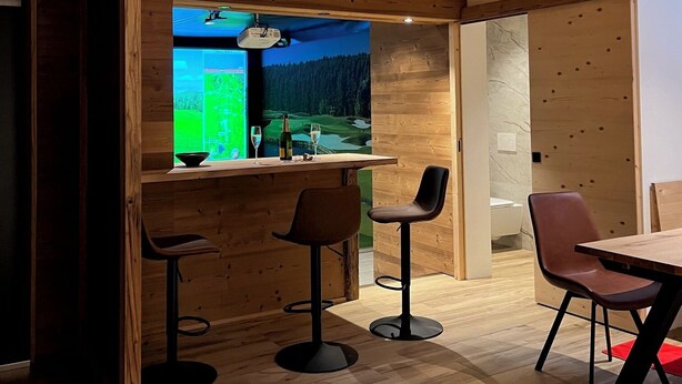 A modern interior with wooden walls, a bar area, and a dining space. - New vacation apartment in the middle of the SkiArena Andermatt Sedrun with indoor golf course (Camischolas)