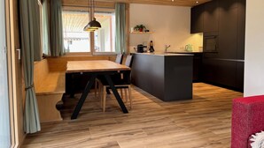 A modern kitchen with a wooden ceiling, a central island, and built-in appliances. - New vacation apartment in the middle of the SkiArena Andermatt Sedrun with indoor golf course (Camischolas)