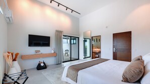A modern hotel room with a large bed, a flat-screen TV, a sliding glass door to a balcony, and a small seating area with a table and chairs. - Areia Boutique Hotel - Puerto Morelos (Puerto Morelos)