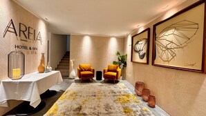 A hotel lobby with a modern design, featuring a reception desk, two armchairs, a staircase, and artwork on the walls. - Areia Boutique Hotel - Puerto Morelos (Puerto Morelos)