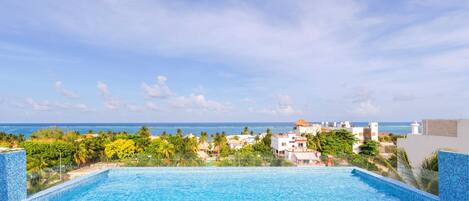 A swimming pool with a view of the ocean and buildings in the background.