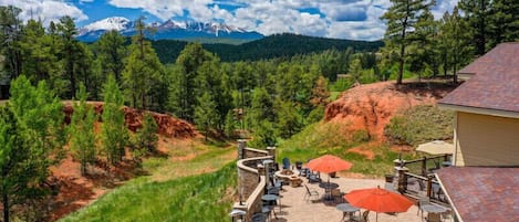 A patio with outdoor seating and a view of a mountainous landscape.