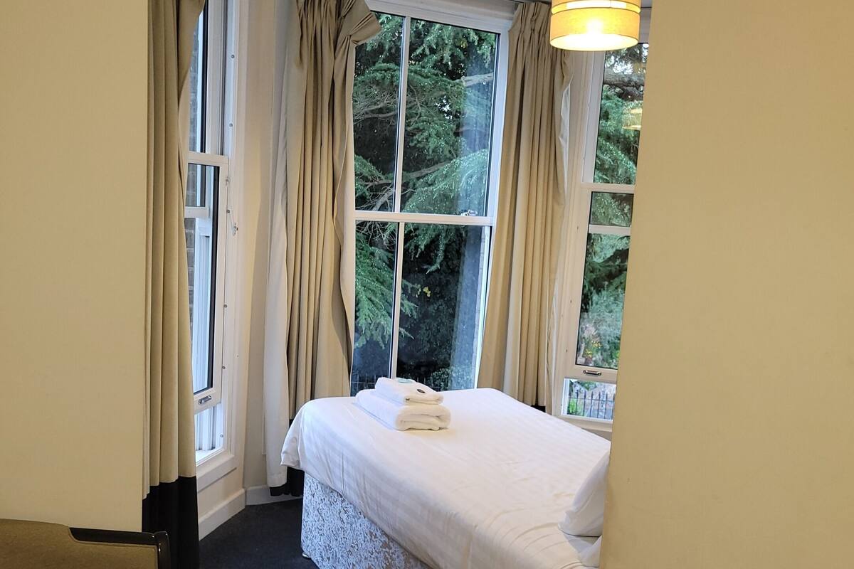 Une chambre d’hôtel avec un lit, un bureau et une fenêtre avec des rideaux.