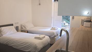 A hotel room with two beds, a wooden counter with a sink, and a hanging light fixture.