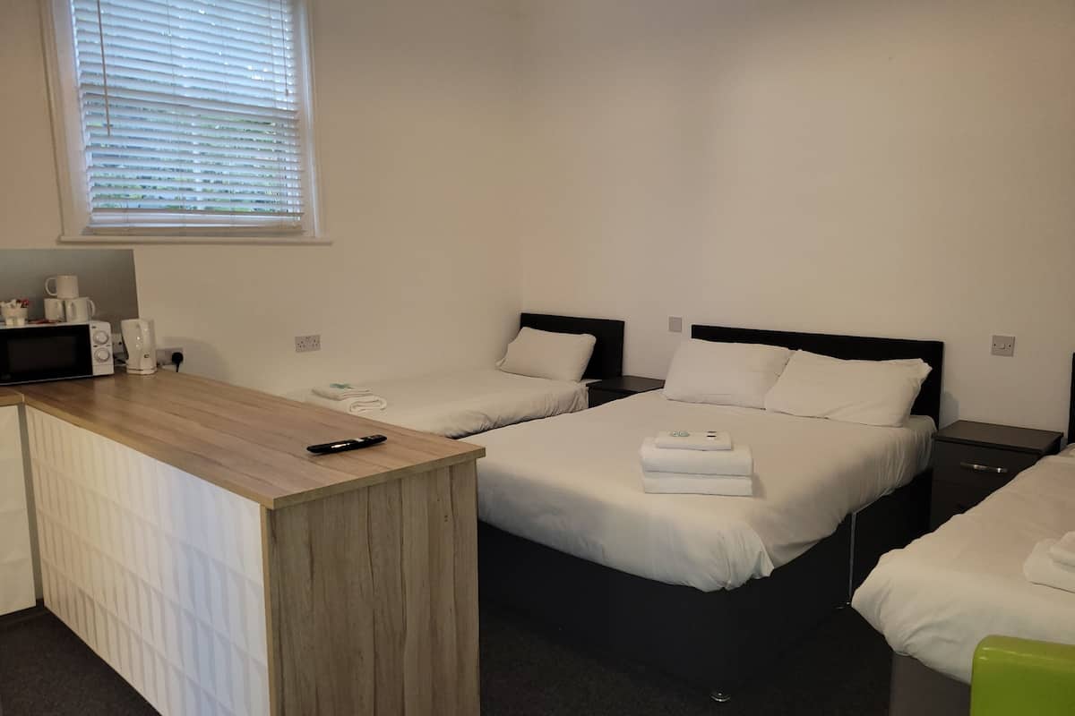 Une chambre d’hôtel avec deux lits, un bureau en bois et une fenêtre avec des stores.