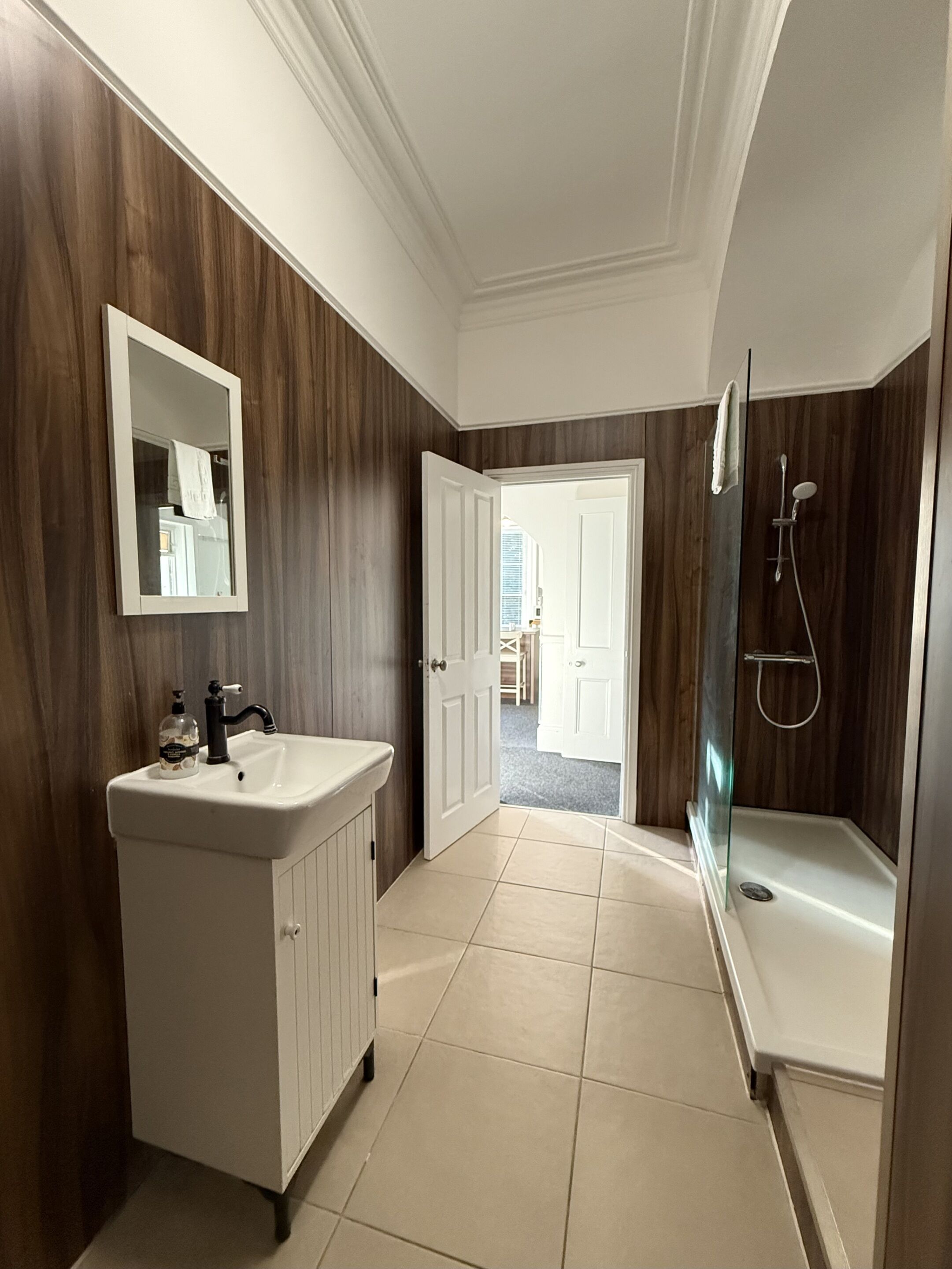 A bathroom with a vanity, mirror, and shower.