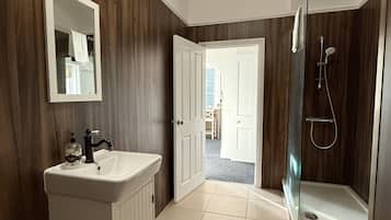 A bathroom with a vanity, mirror, and shower.