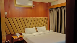 Camera d'albergo con un letto grande, una testiera in legno, un comodino con una lampada e un condizionatore d'aria a parete.