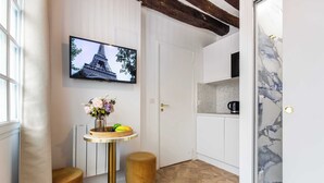 Una cocina moderna con salpicadero de mármol, un televisor de pantalla plana sobre la encimera y una mesita redonda con un jarrón de flores.