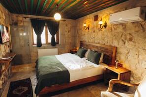 Une chambre à coucher rustique avec un mur en pierre, un lit en bois, une table de chevet et une chaise.