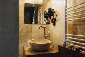 Une salle de bain avec un meuble-lavabo en bois, un grand lavabo sur pied, un miroir et un porte-serviettes.