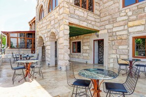 Une terrasse extérieure avec des murs en pierre, plusieurs tables et des chaises.