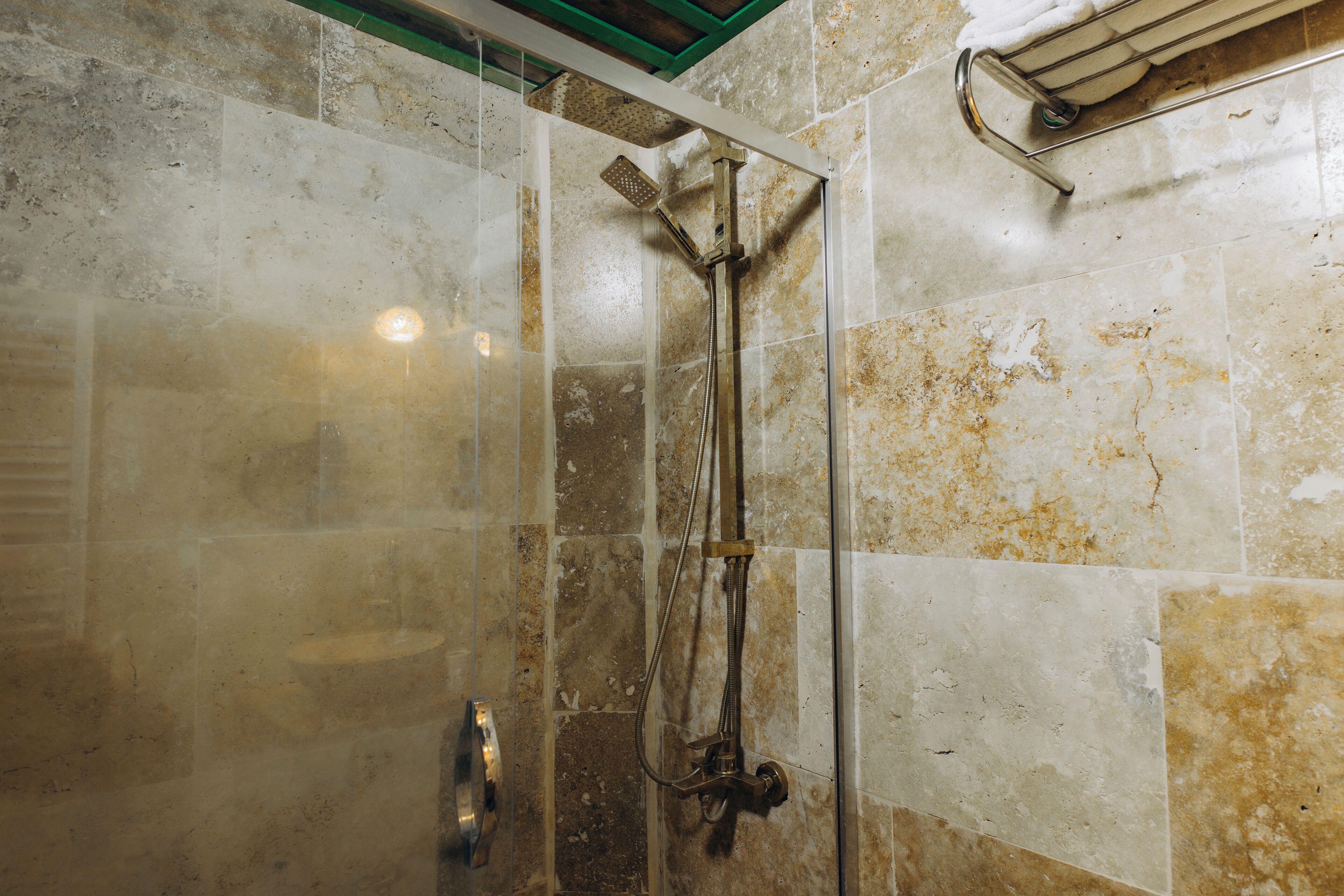 Ducha con puerta de vidrio, cabezal de ducha de mano y toallero adherido a la pared.