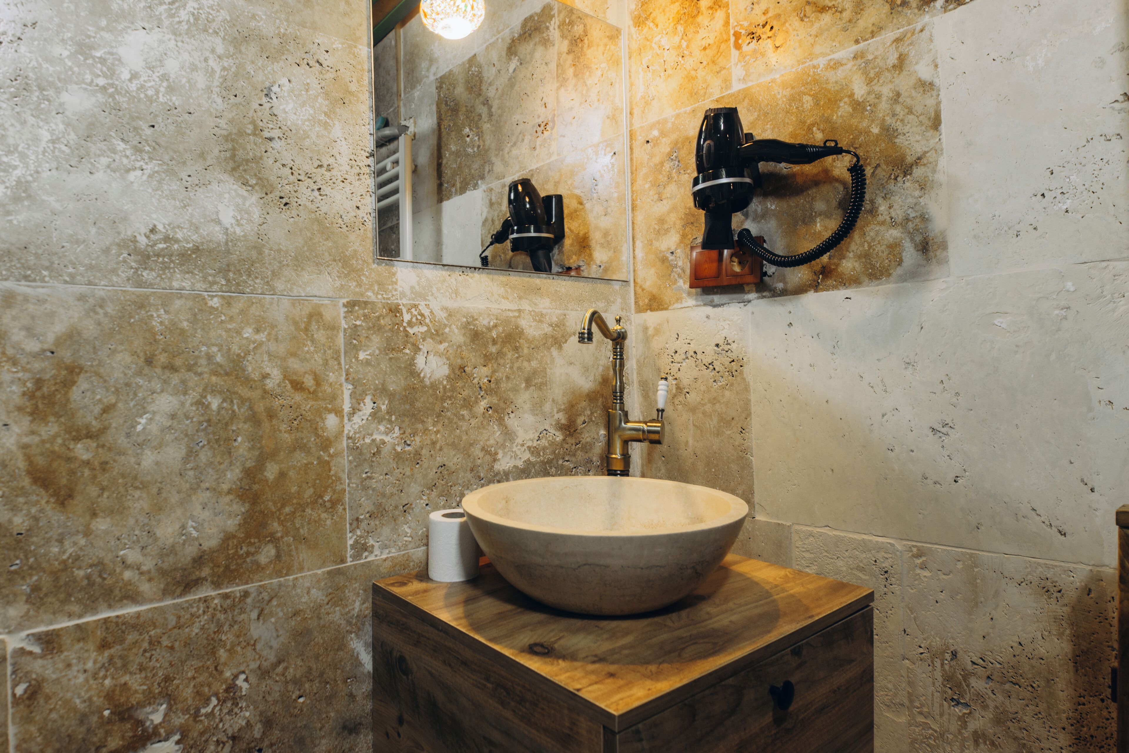 Une salle de bain avec un grand lavabo rond de couleur beige, posé sur un meuble-lavabo en bois, un miroir au-dessus du lavabo et un porte-serviettes fixé au mur.