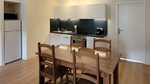 A compact kitchen with white cabinets, a black countertop, and a built-in oven. - Gentiane *** 5 people (Bagnères-de-Luchon)