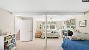 Un dormitorio con cama, televisor, estanter ía y silla.