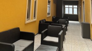 A yellow-walled indoor area with wicker furniture, a tiled floor, and a vertical garden. - Guest House Acácias Rubras (Ferreira do Zezere)