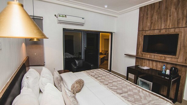 Habitación de hotel con cama, escritorio, televisor, aire acondicionado y puerta corredera.