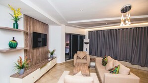 Una sala de estar moderna con un conjunto de sofá, una mesa de centro, un televisor montado en un panel de madera y una lámpara de techo.