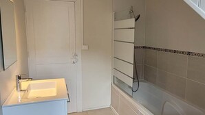A modern bathroom with a white vanity, a bathtub, and a shower.