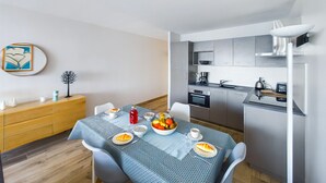 A compact kitchen with modern appliances, a dining area with a table set for two, and a minimalist decor.
