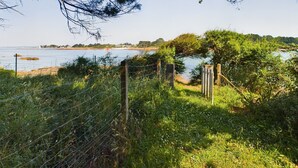 Paesaggio naturale con specchio d'acqua, recinzione in legno e cancello.