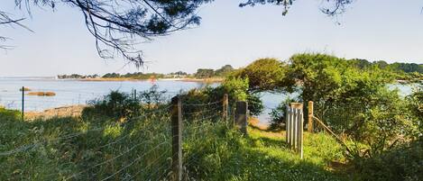 A natural landscape with a body of water, a wooden fence, and a gate.