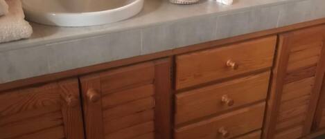A bathroom with two sinks, wooden cabinets, and a mirror.