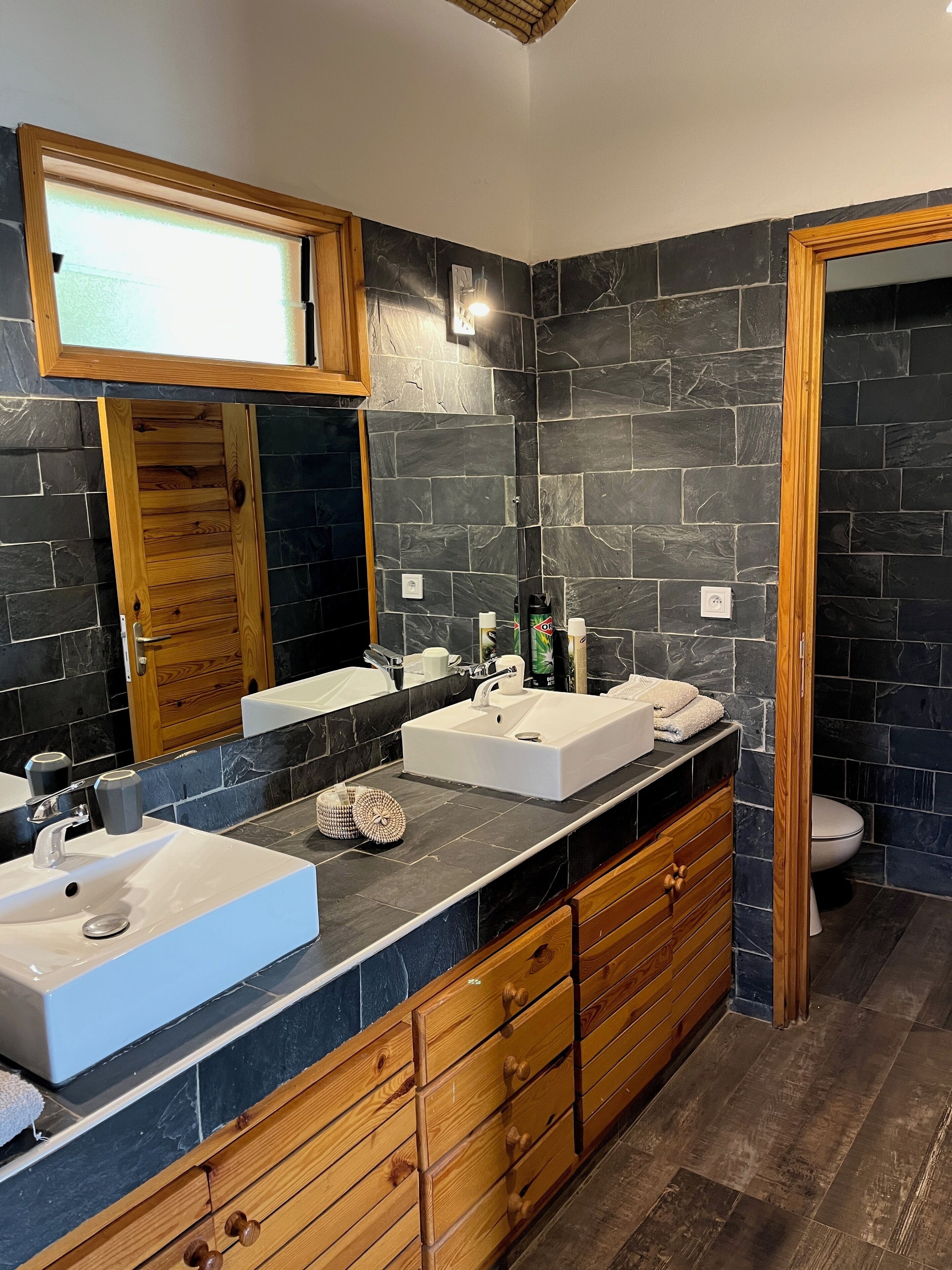Un baño moderno con dos lavamanos, un mueble de tocador de madera y un espejo grande.