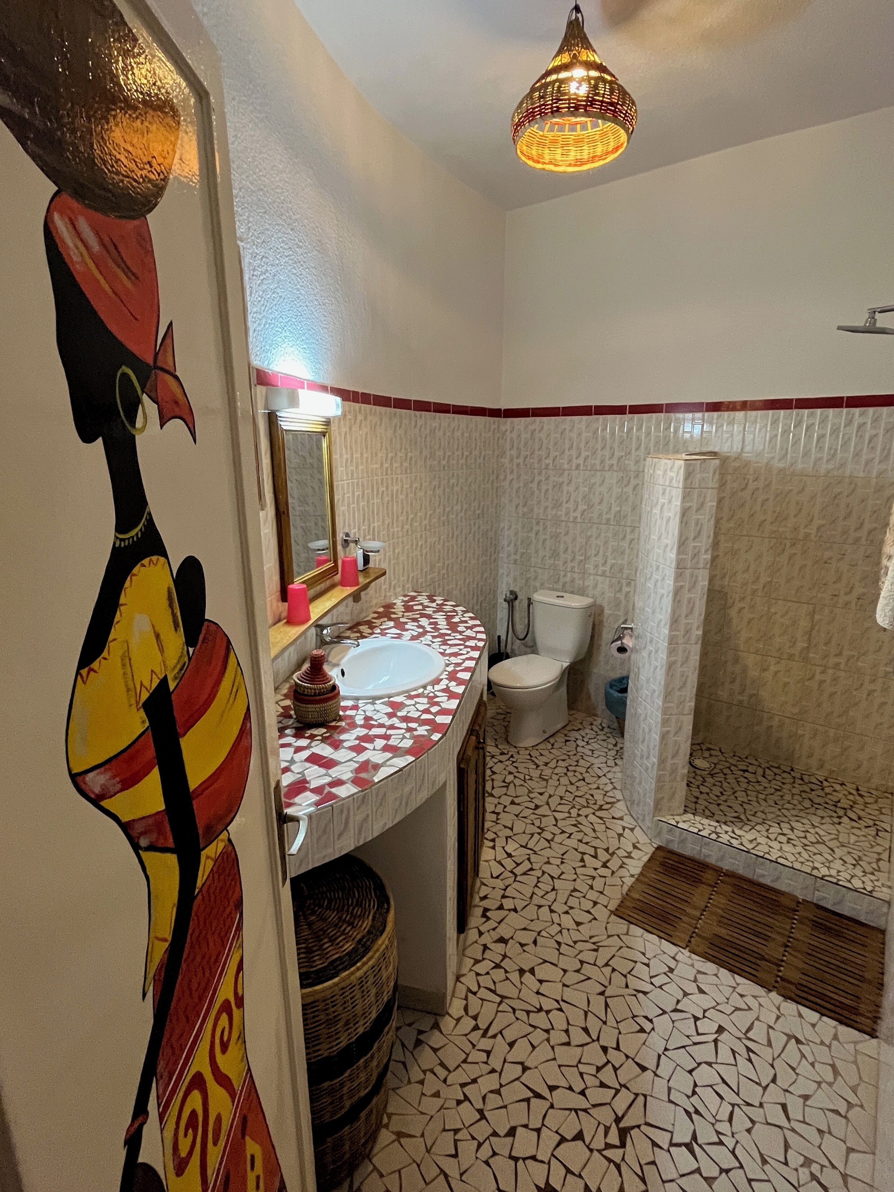 A bathroom with a mosaic floor, a sink, a toilet, and a shower.