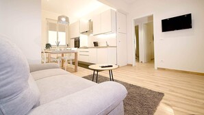 Un salon moderne avec un canapé, une petite table ronde et un coin cuisine à l’arrière-plan.