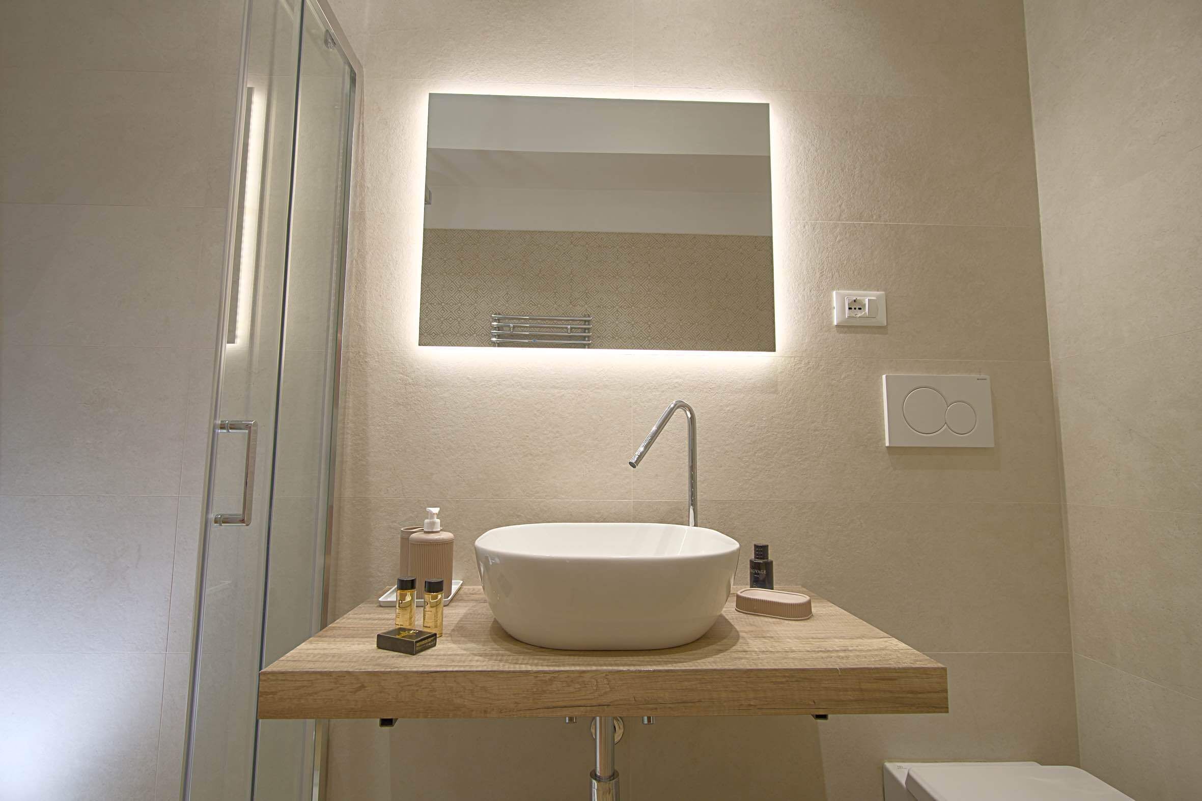 A modern bathroom with a large oval sink, a mirror, and a wooden countertop.