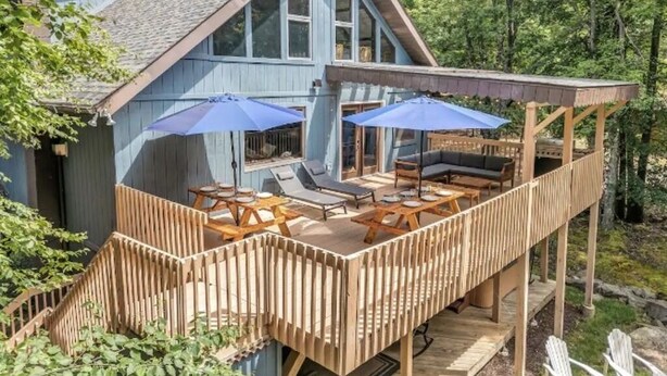 Una cabaña con terraza, mobiliario exterior y un espacio cubierto.