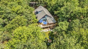 Una casa rodeada de un bosque frondoso, con una amplia terraza y zona de estar al aire libre.