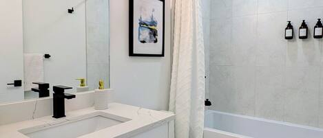 A modern bathroom with a white vanity, a toilet, and a bathtub.