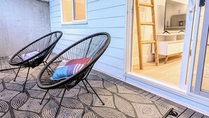 A covered patio with two wicker chairs and a patterned rug. - Modern 2BR Suite | Private Patio | 5 Min Downtown/Zoo/Stampede | Central & Safe (Calgary)
