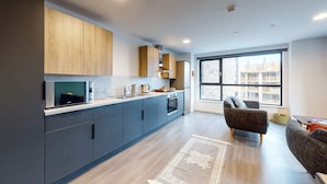 Une cuisine moderne avec des meubles de couleur sombre, un four à micro-ondes et une grande fenêtre offrant une vue sur la ville.