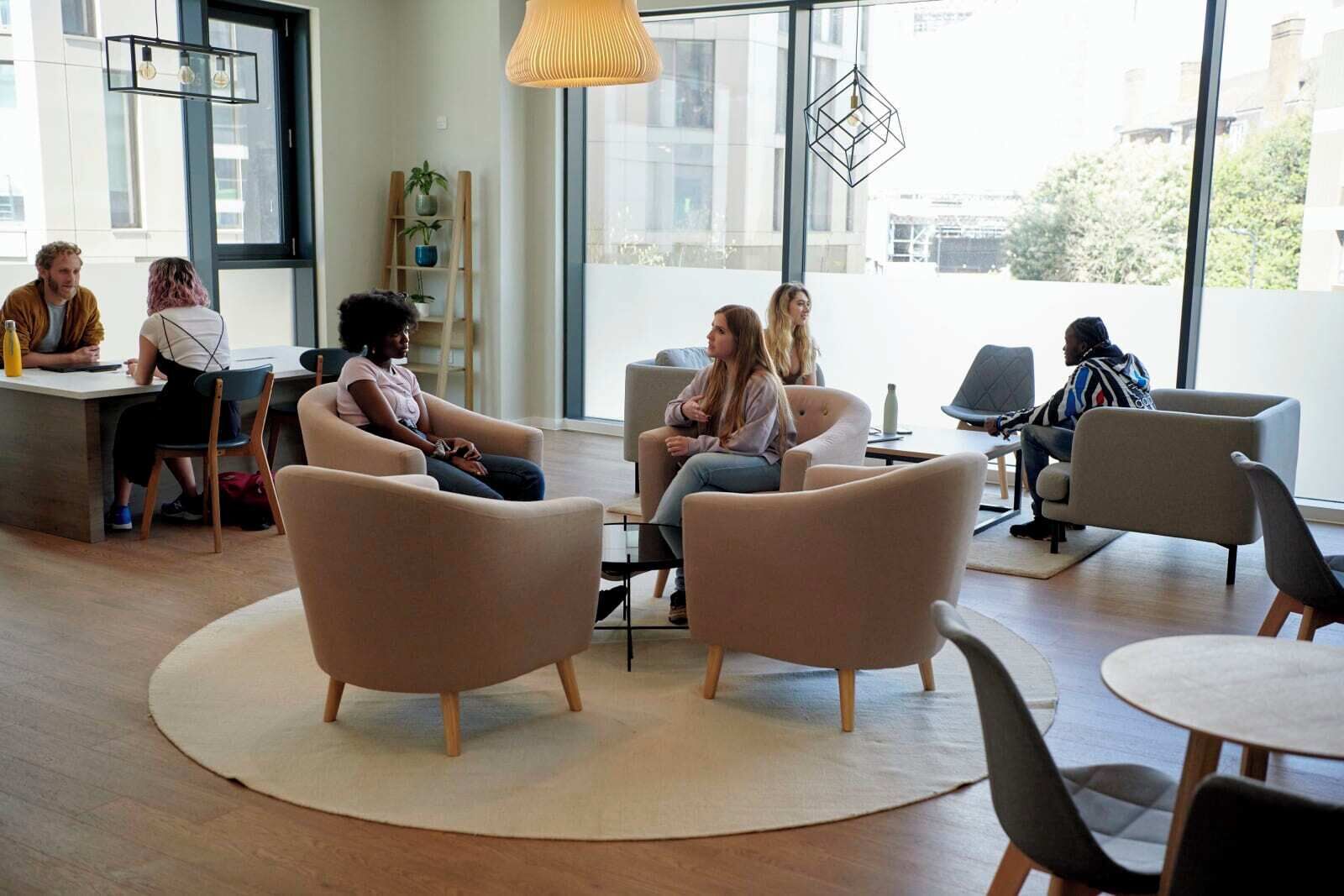 A modern co-working space with round tables and comfortable seating areas.