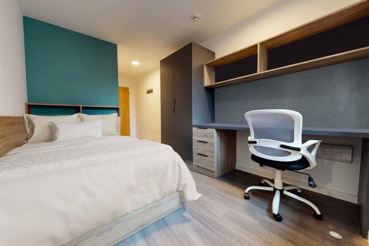 A modern hotel room with a bed, a desk, and a chair.