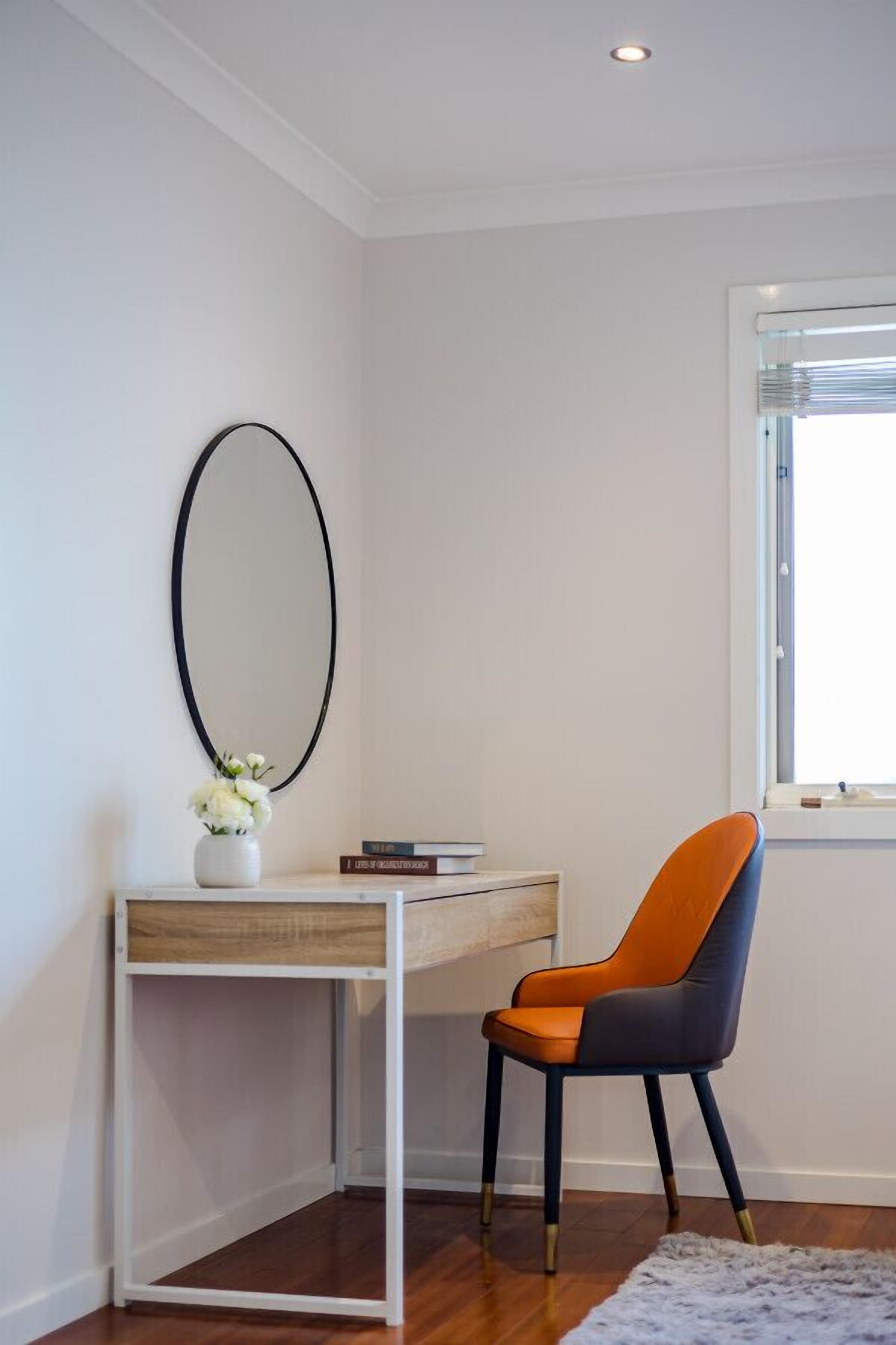 A corner room with a desk, chair, and a large mirror on the wall.