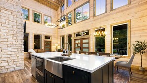 A spacious kitchen with a large island, black cabinetry, and a stone accent wall. - 3BR Forest Hideaway! Playset, Pool Table, Foosball (Broken Bow)
