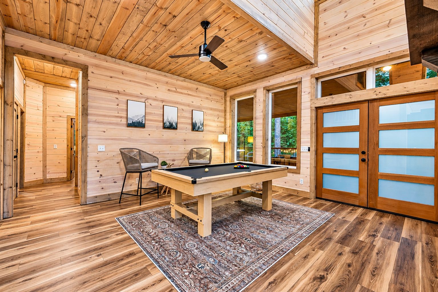 Interior de madera con mesa de billar, sillas y un ventilador de techo.