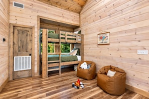 A wooden cabin interior with bunk beds, a door, a vent, and two bean bags. - Playset & Pool Table | Hot Tub | Sleeps 14 (Broken Bow)