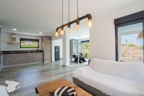 A modern living space with a kitchen, dining area, and a large window offering a view of the outdoors. - CostaBlancaDreams - Casa Sereno in Calpe (Calpe / Calp)