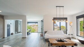A modern living room with a sofa, a coffee table, and a view of a mountainous landscape through large windows. - CostaBlancaDreams - Casa Sereno in Calpe (Calpe / Calp)