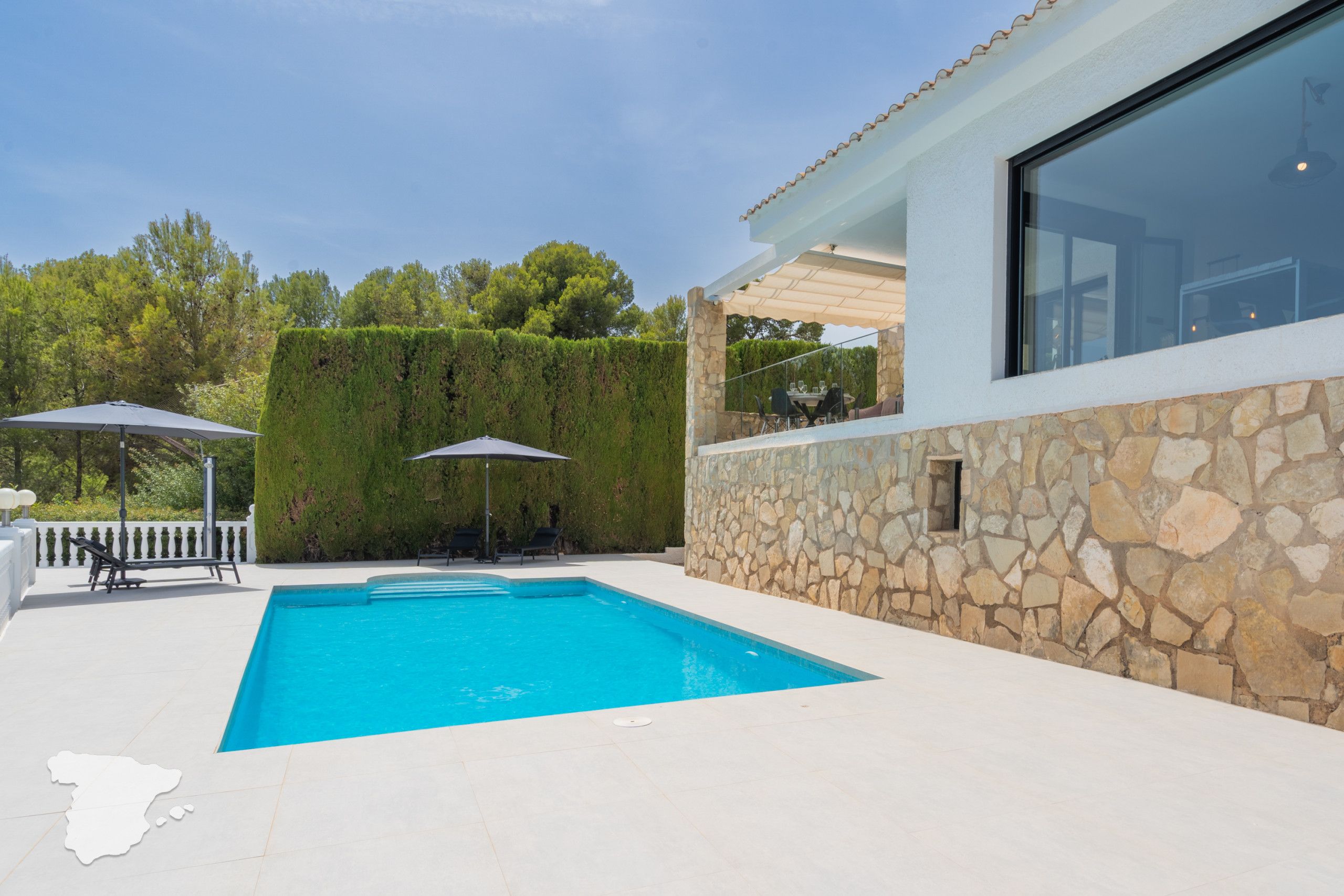 A swimming pool with a stone wall and a glass window.
