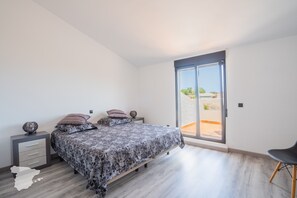 A bedroom with a bed, a nightstand, a chair, and a sliding glass door leading to an outdoor area. - CostaBlancaDreams - Casa Sereno in Calpe (Calpe / Calp)