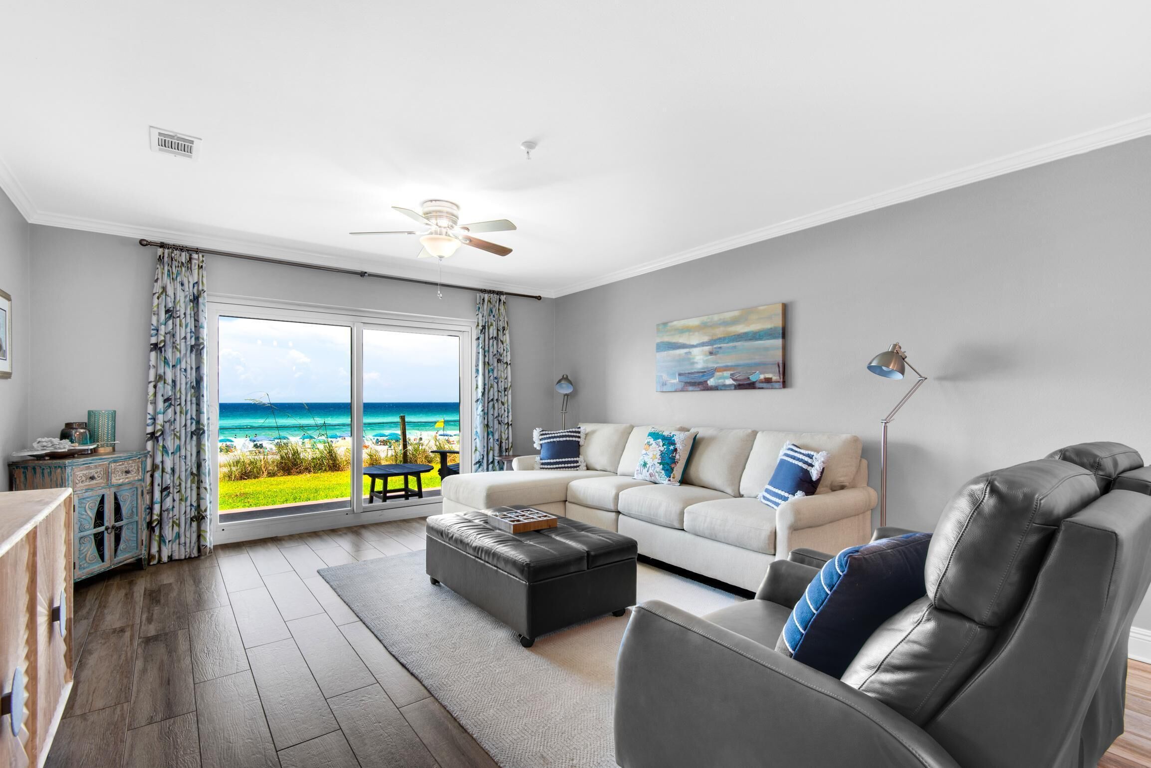 Een moderne woonkamer met een grote schuifglazen deur naar een balkon met uitzicht op zee.